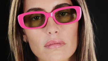 Pembe gözlüklü güzel bir kadın etrafa bakıyor.