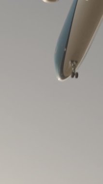 Günbatımında dikey olarak süper yavaş çekimde havalimanına iniş yapmak için üzerimizden uçan uçak