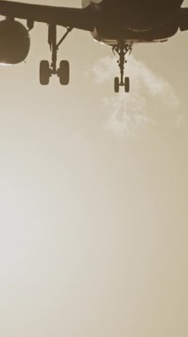 Günbatımında dikey olarak süper yavaş çekimde havalimanına iniş yapmak için üzerimizden uçan uçak