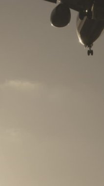 Günbatımında dikey olarak süper yavaş çekimde havalimanına iniş yapmak için üzerimizden uçan uçak