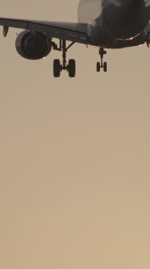 Günbatımında dikey olarak süper yavaş çekimde havalimanına iniş yapmak için üzerimizden uçan uçak