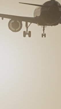 Günbatımında dikey olarak süper yavaş çekimde havalimanına iniş yapmak için üzerimizden uçan uçak