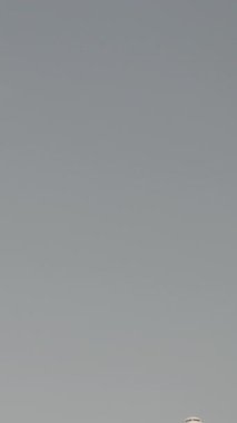 Günbatımında dikey olarak süper yavaş çekimde havalimanına iniş yapmak için üzerimizden uçan uçak