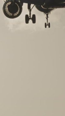 Günbatımında dikey olarak süper yavaş çekimde havalimanına iniş yapmak için üzerimizden uçan uçak