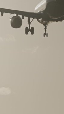 Günbatımında dikey olarak süper yavaş çekimde havalimanına iniş yapmak için üzerimizden uçan uçak