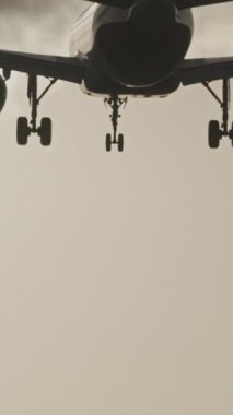 Günbatımında dikey olarak süper yavaş çekimde havalimanına iniş yapmak için üzerimizden uçan uçak