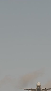 Günbatımında dikey olarak süper yavaş çekimde havalimanına iniş yapmak için üzerimizden uçan uçak