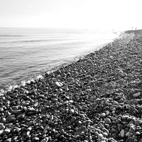 Piedra en la costa amanecer y sombrilla — Foto de Stock