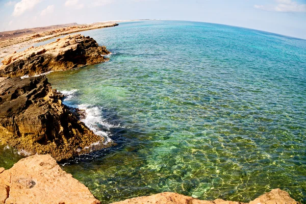 В прибрежных водах Черного моря скала и пляж отдыхают под небом — стоковое фото