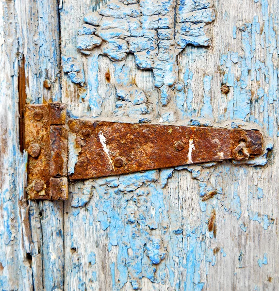 Chiodo in metallo arrugginito vernice sporca spogliata nella porta di legno blu — Foto Stock