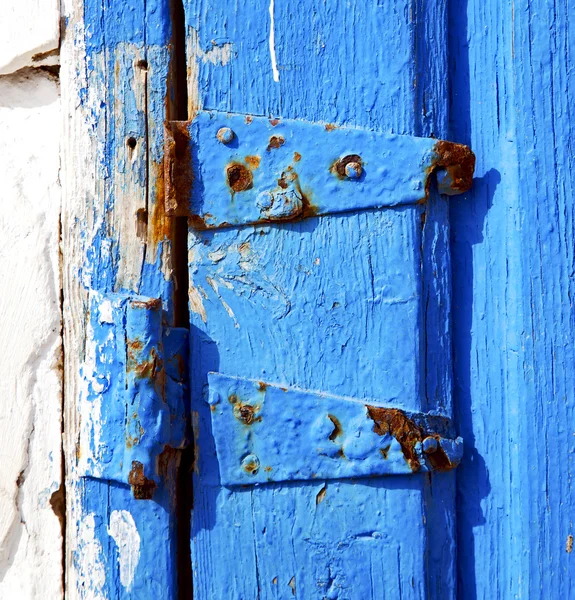 Zardzewiały metal paznokci brudne pozbawione farby w niebieskie drzwi z drewna — Zdjęcie stockowe