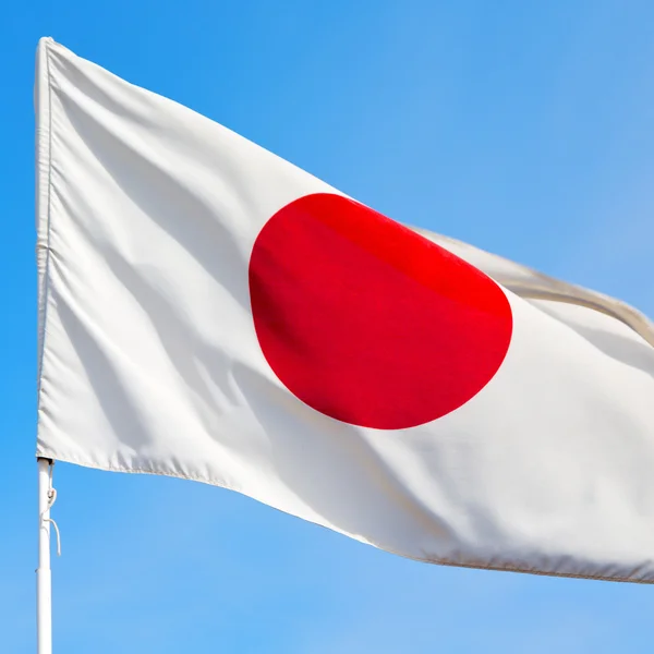 Japanb acenando bandeira no céu azul bcolor e onda — Fotografia de Stock