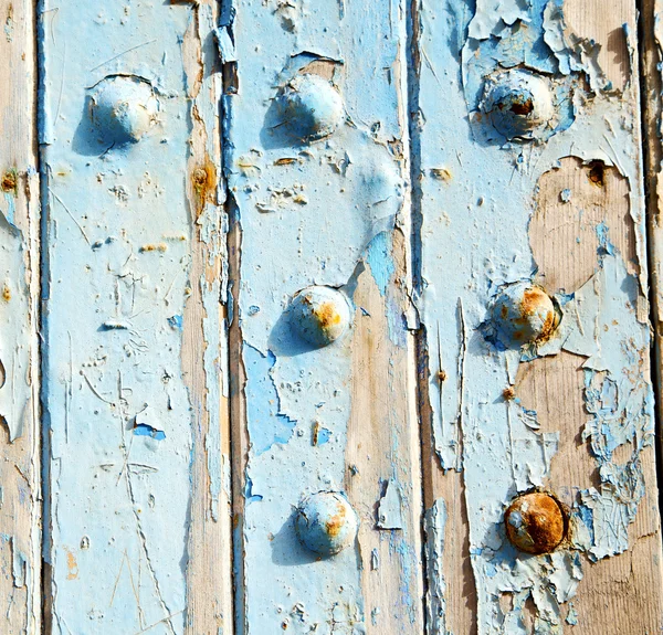 Stripped paint in the blue wood door and rusty nail — Stock Photo, Image