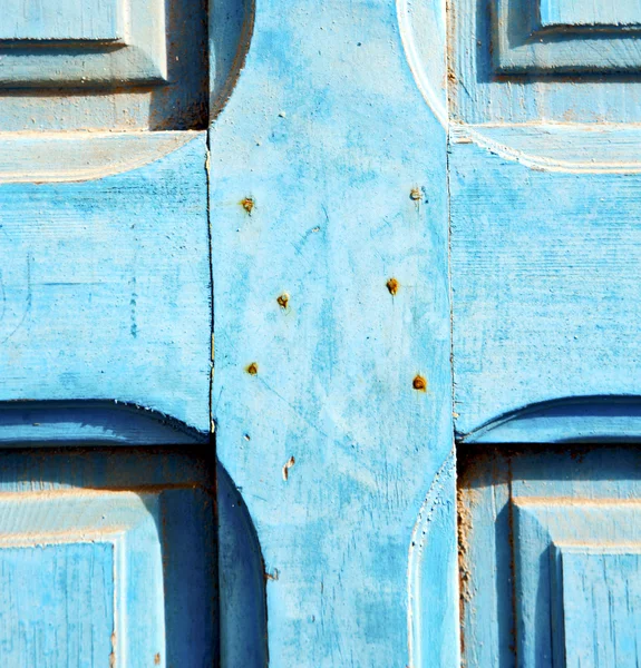 Dirty stripped paint in the blue wood door and rusty nail — Stock Photo, Image