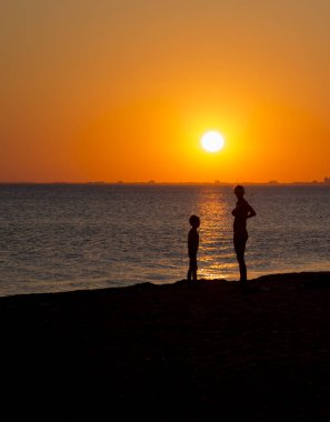 İnsanlar gün batımında deniz kıyısında