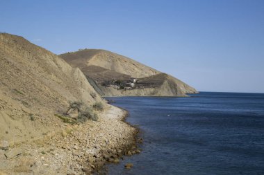 Deniz kıyısı kayalıklarla bir körfeze sıkışmış.