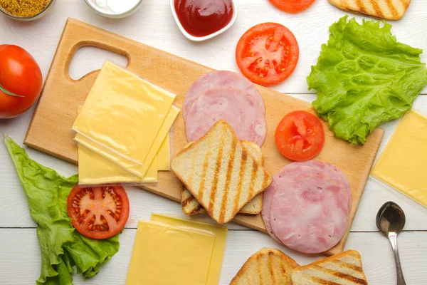 Sandwich. Ingredients for making sandwiches on a board of bread, ham, cheese, tomato on a white background