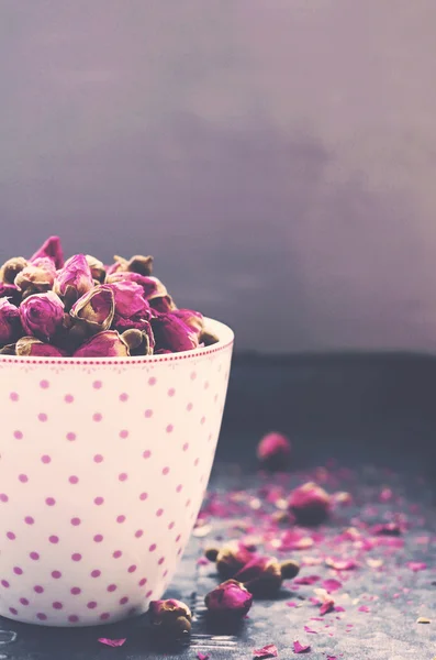 Rosas secas en taza de té rosa con copyspace sobre fondo gris — Foto de Stock