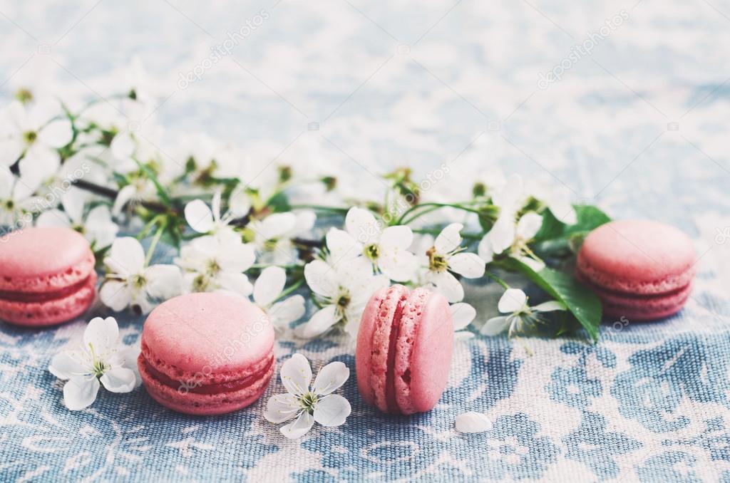 Pink macaroons and blooming cherry flowers at vintage tablecloth
