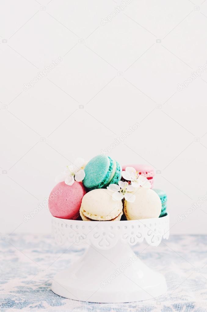 Macaroons decorated with white flowers on cake stand