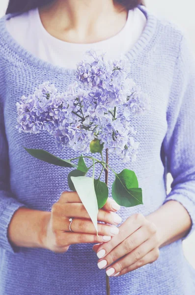 Woman in knitted sweater holding lilac flower in her hands — Stock Photo, Image