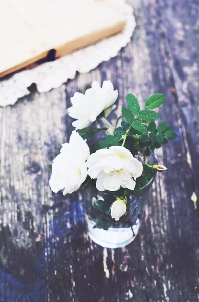 Mazzo di rose selvatiche in un bicchiere sul tavolo da giardino estivo — Foto Stock