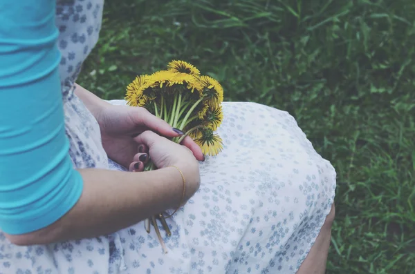 Sarı dandelions onun elinde tutan genç kadın — Stok fotoğraf