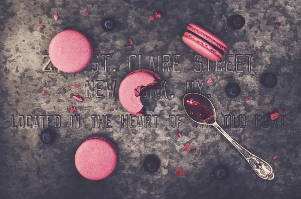 Рожеві макаруни та свіжа чорниця на металевому фоні — стокове фото