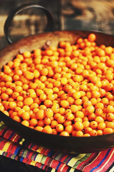 Bayas de espino cerval de mar en cuenco de latón rústico, estilo granja — Foto de Stock