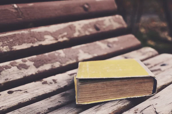 Libro viejo de tapa dura en banco de madera en el parque del otoño —  Fotos de Stock