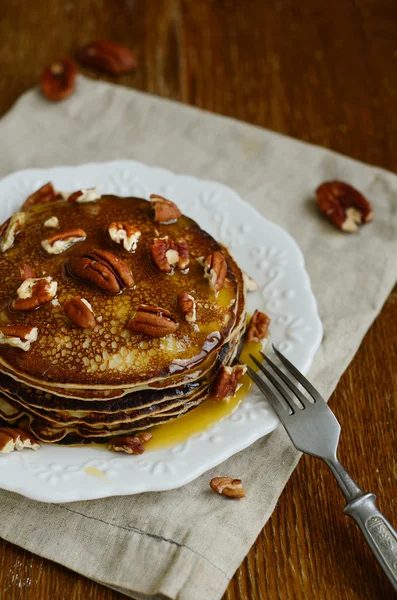 Pila de panqueques finos caseros coronados con miel y nueces de pacana — Foto de Stock