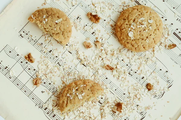 Hausgemachte Haferflockenplätzchen mit Walnuss auf Notenblättern — Stockfoto