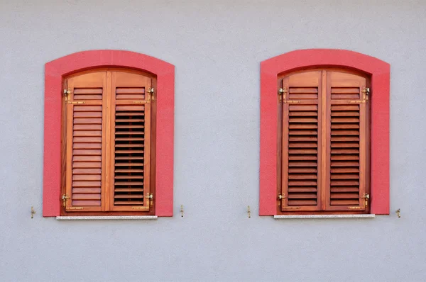 Two red windows with wooden jalousie on white wall — Stock Photo, Image