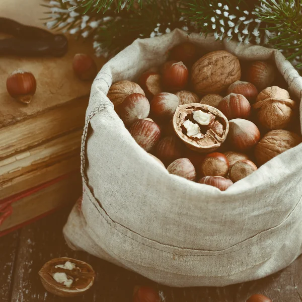 Winter decoration with nuts, xmas tree branch, pile of vintage b — Stock Photo, Image