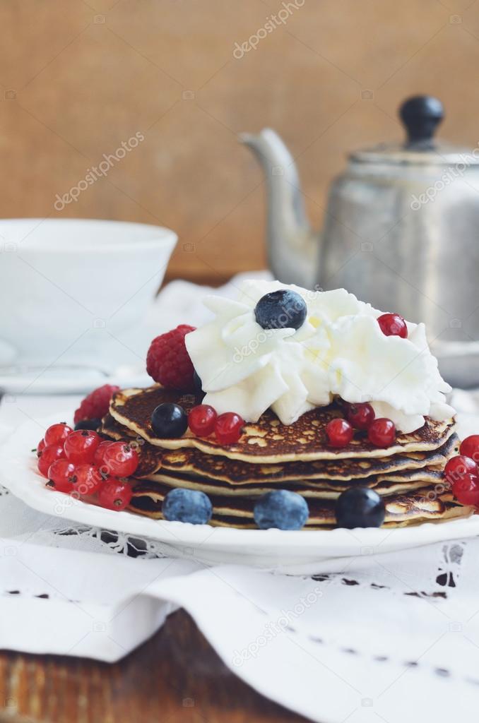 Coffee time with homemade pancakes with cream and fresh berries