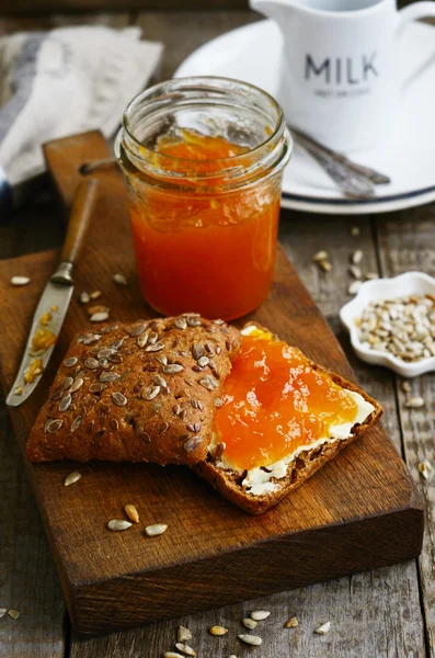 Ontbijt met roggebrood, abrikozenjam, zonnebloempitten en melk — Stockfoto