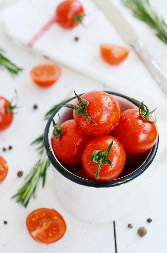Ripe tomato in metal bowl, fresh rosemary and black pepper