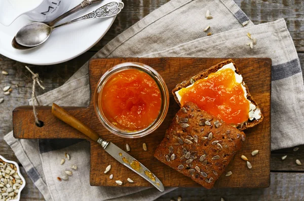 Ontbijt met roggebrood, abrikozenjam, zonnebloempitten en melk — Stockfoto