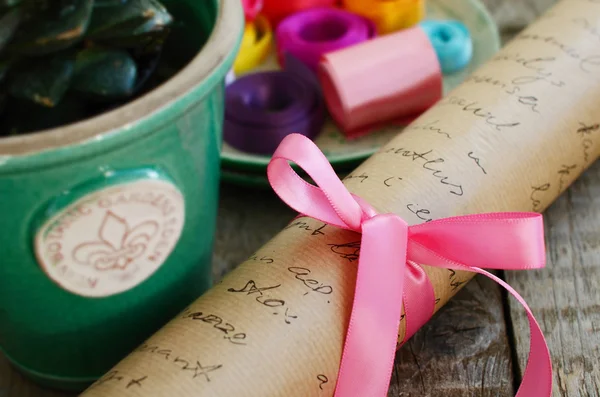 Wrapping paper roll with pink bow and colorful ribbons — Stock Photo, Image