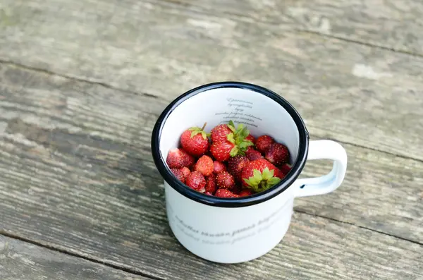 Wild strawberry in metal cup on wooden table — Stock Photo, Image