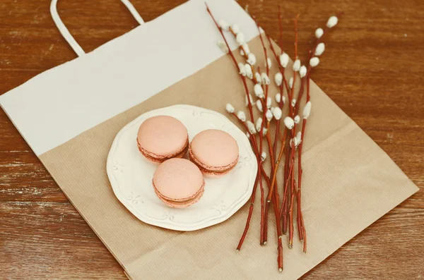 Karamell-Macarons auf weißem Teller und Pussy Weidenstrauß — Stockfoto