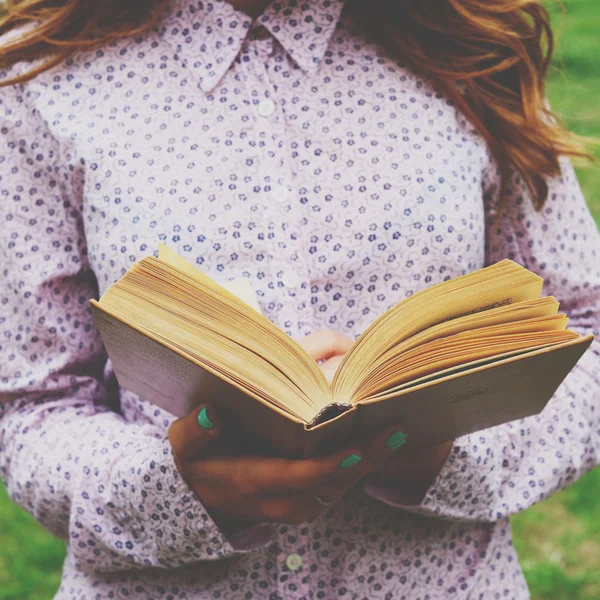 Jovem segurando livro aberto em suas mãos — Fotografia de Stock