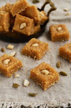Homemade burfi - traditional indian sweets with coconut flakes, cardamom and cashew nut clipart