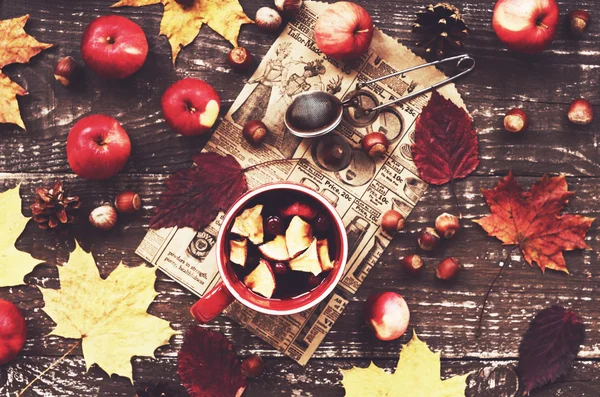 Чашка чая с яблоками, клюквой и желтыми кленовыми листьями — стоковое фото