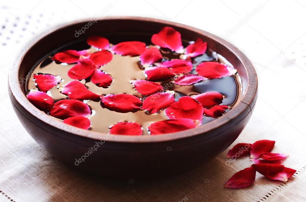 Wooden bowl with floating red rose petals