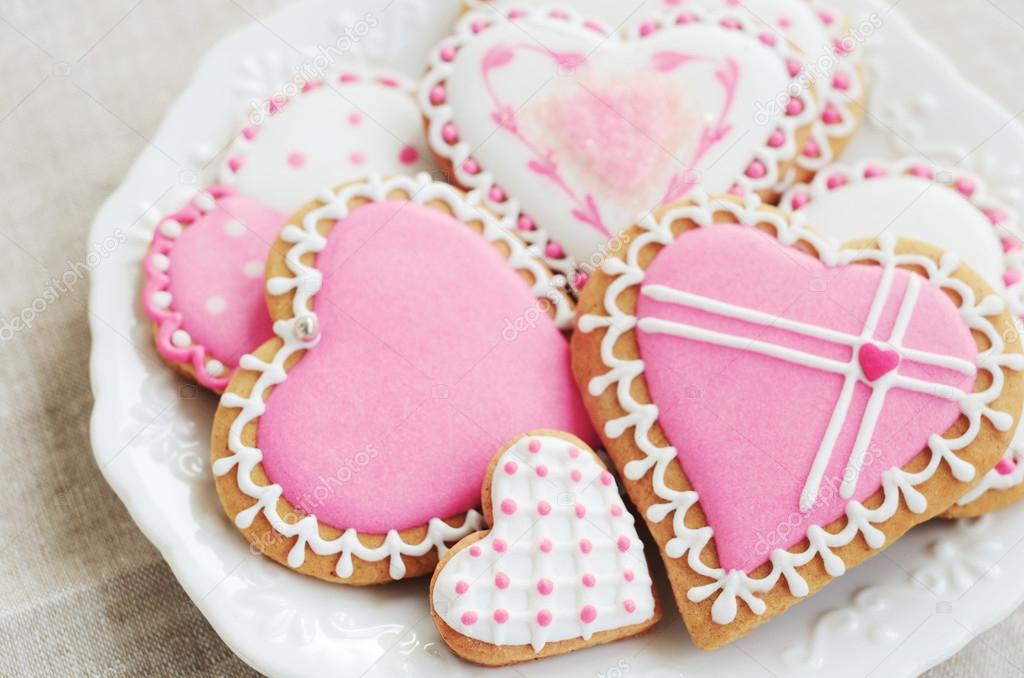 Homemade heart shaped sugar cookies with icing on white plate