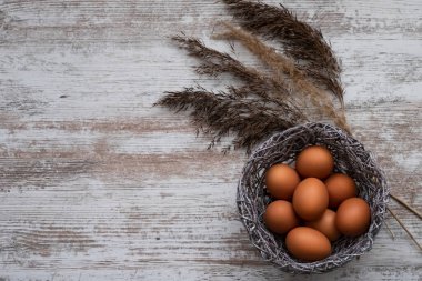 Gri ahşap bir masada paskalya yumurtaları. Yumurta ve bitki dallarıyla Paskalya modeli