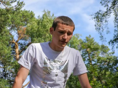 Bronzlaşmış, üzgün yüzlü genç bir adamın portresi, yaz güneşli bir gün.