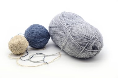 Beyaz arka planda üç top iplik, farklı renkler ve boyutlarda. Fotoğraflar soğuk tonda.