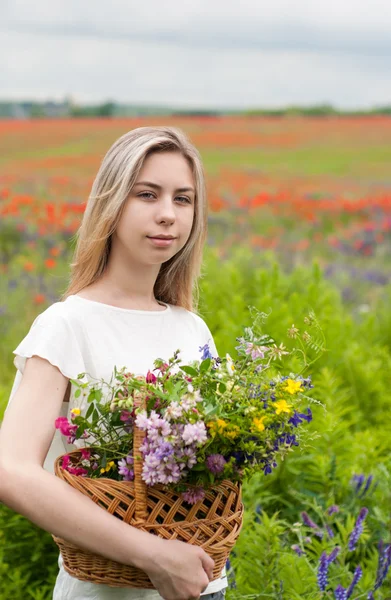 Vacker blond flicka med korg med blommor — Stockfoto